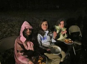 Three girls enjoying snacks at the bonfire