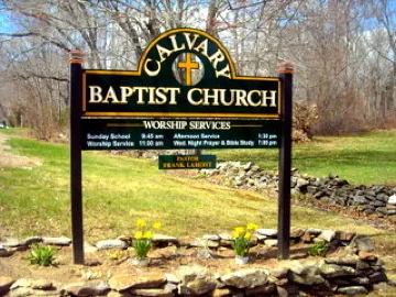 The Calvary Baptist Church sign with worship service times, daffodils in front